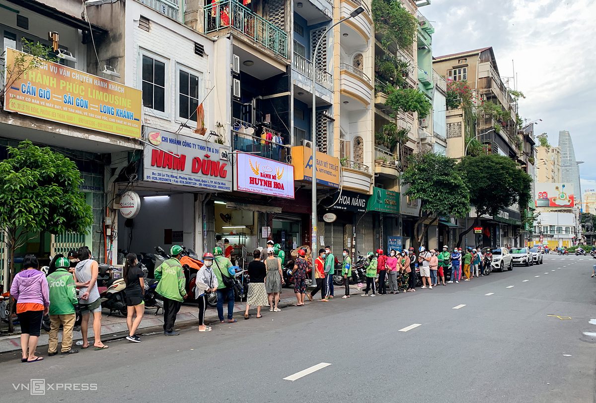A long line of customers and shippers wait their turn in front of the Huynh Hoa stall on Le Thi Rieng Street in District 1, which has been operating for over 30 years. Nguyen Quang Huy, 37, the owner, said the shop has been as crowded as before the pandemic since the city eased social distancing measures.